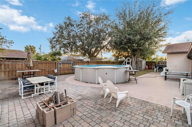 view of patio featuring a fenced in pool, a fire pit, and a storage unit