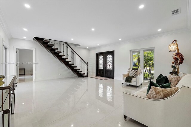 entryway with ornamental molding and french doors