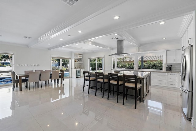 tiled dining space featuring beam ceiling, sink, and ornamental molding