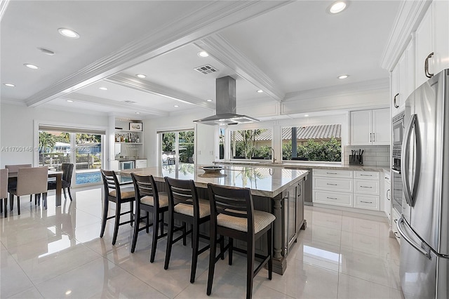 kitchen featuring a spacious island, white cabinets, appliances with stainless steel finishes, island exhaust hood, and beamed ceiling