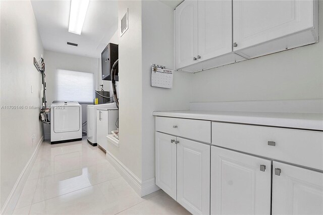 clothes washing area featuring light tile patterned floors, water heater, and washer and clothes dryer