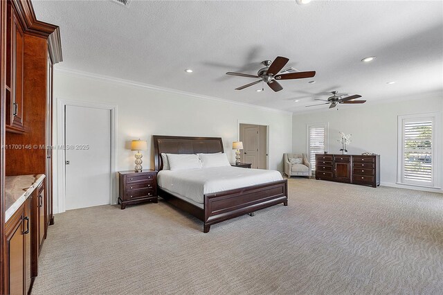 bedroom with ceiling fan, a textured ceiling, ornamental molding, and light carpet