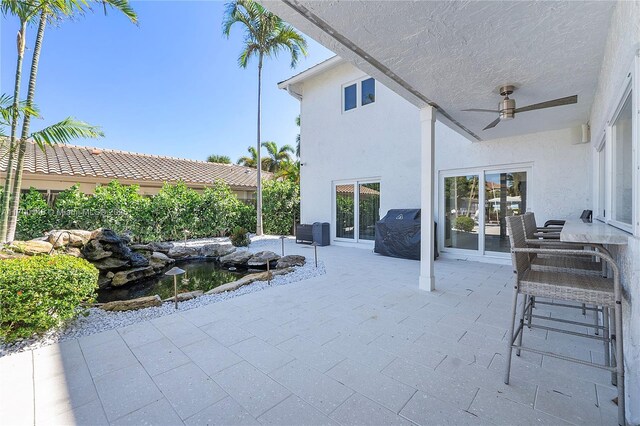 view of patio / terrace with ceiling fan and a bar