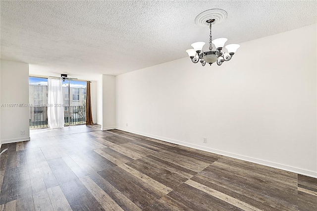 empty room with ceiling fan with notable chandelier, dark hardwood / wood-style flooring, expansive windows, and a textured ceiling