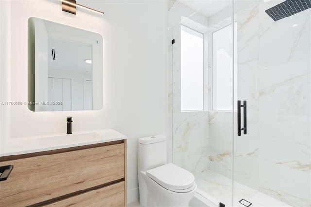 bathroom featuring vanity, toilet, and a shower with shower door