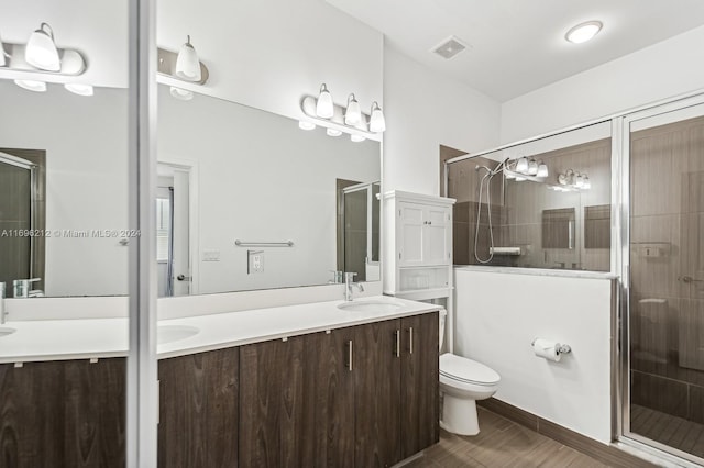 bathroom with hardwood / wood-style floors, vanity, a shower with shower door, and toilet