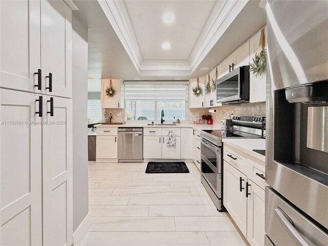 kitchen featuring white cabinets, a raised ceiling, sink, and stainless steel appliances