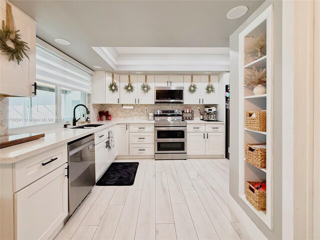 kitchen featuring backsplash, white cabinetry, sink, and stainless steel appliances