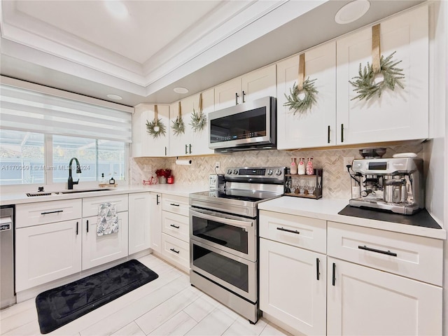 kitchen with white cabinets, sink, stainless steel appliances, and tasteful backsplash