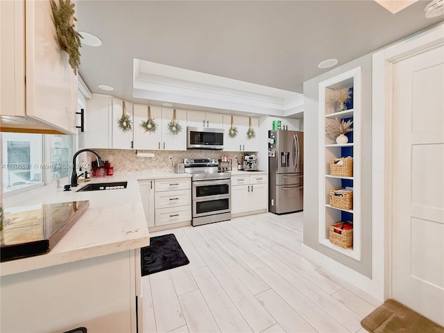 kitchen featuring light stone countertops, backsplash, stainless steel appliances, sink, and white cabinets