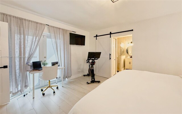 bedroom with a barn door, connected bathroom, and multiple windows