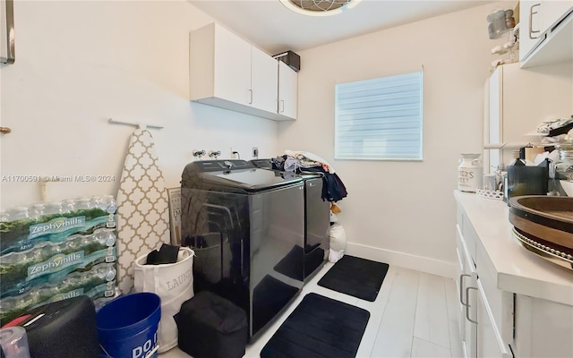 clothes washing area with cabinets and washer and dryer