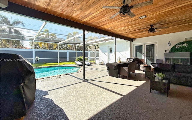 exterior space with french doors, a lanai, an outdoor living space, ceiling fan, and a fenced in pool