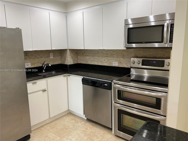 kitchen featuring tasteful backsplash, light tile patterned flooring, white cabinets, and stainless steel appliances