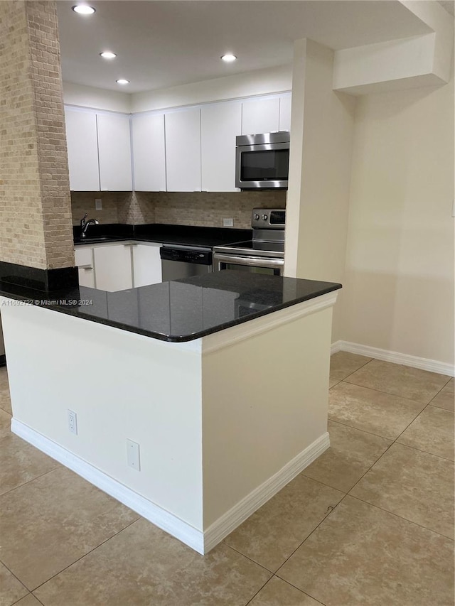 kitchen with decorative backsplash, appliances with stainless steel finishes, and white cabinetry