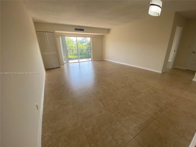 spare room with light tile patterned floors and a textured ceiling