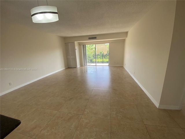 tiled spare room featuring a textured ceiling