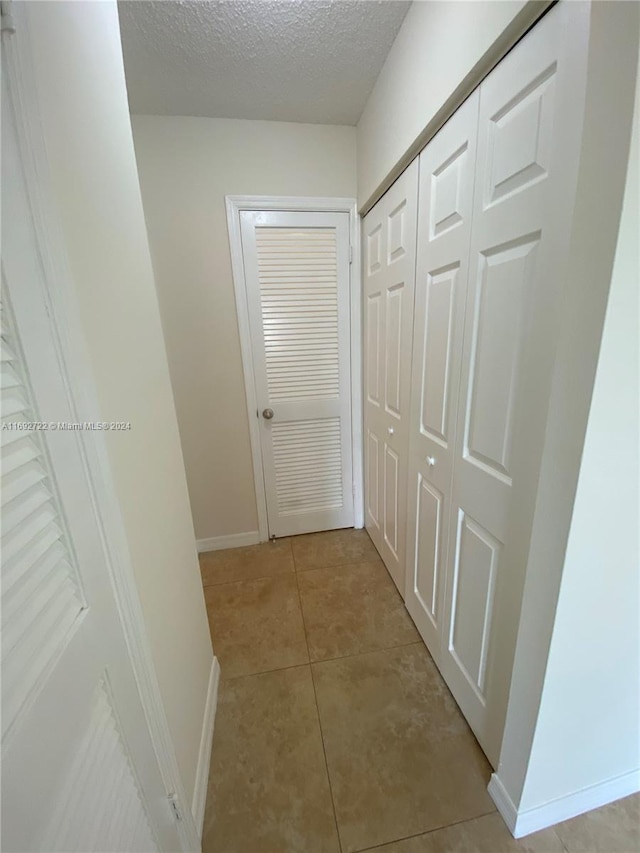 corridor featuring light tile patterned floors and a textured ceiling