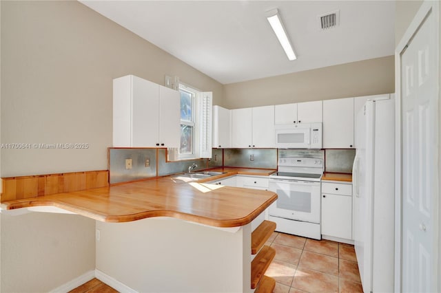 kitchen with white cabinetry, white appliances, kitchen peninsula, and light tile patterned flooring