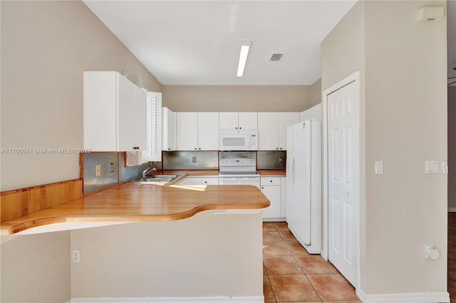 kitchen featuring light tile patterned flooring, white cabinetry, backsplash, kitchen peninsula, and white appliances