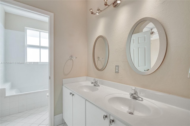 bathroom with a relaxing tiled tub, tile patterned floors, and vanity