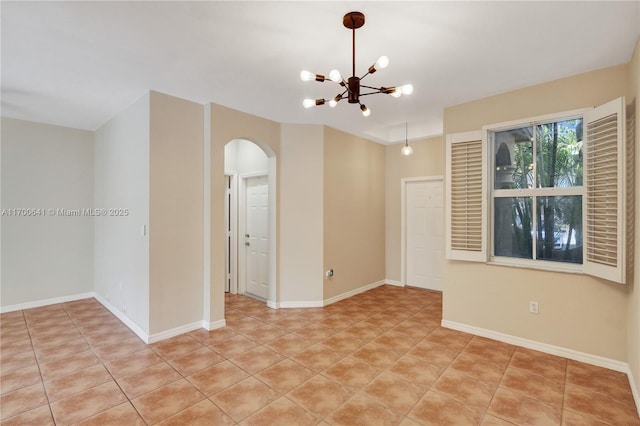 tiled spare room with an inviting chandelier