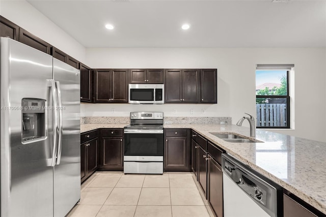 kitchen featuring light stone counters, dark brown cabinets, stainless steel appliances, sink, and light tile patterned floors