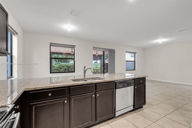 kitchen featuring appliances with stainless steel finishes, light stone counters, dark brown cabinetry, sink, and light tile patterned floors