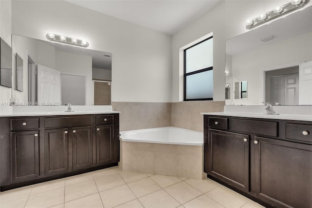 bathroom with tile patterned floors, vanity, and a relaxing tiled tub