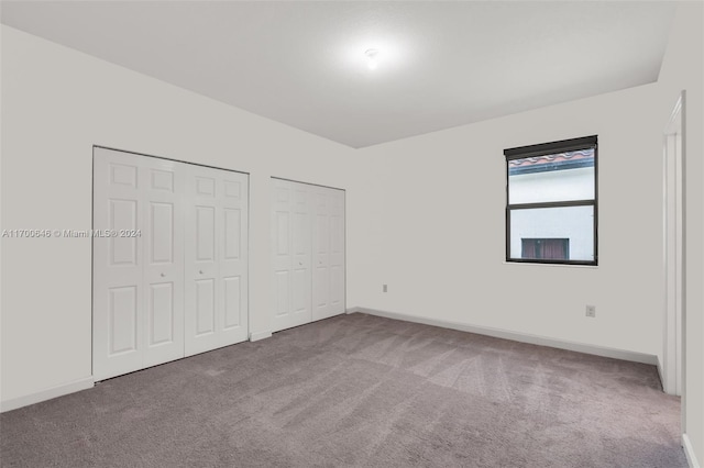 unfurnished bedroom featuring multiple closets and carpet