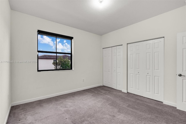 unfurnished bedroom with carpet flooring and multiple closets