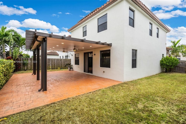 back of property featuring ceiling fan, a yard, and a patio