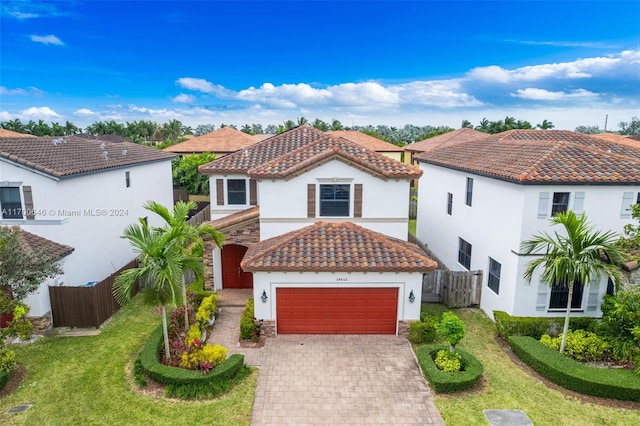 mediterranean / spanish home featuring a front yard and a garage