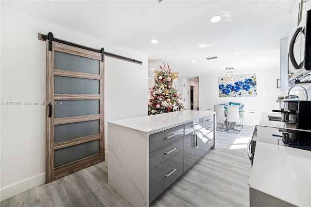 interior space with a barn door, sink, gray cabinetry, and light wood-type flooring