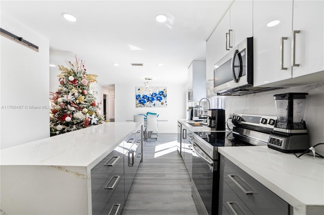 kitchen featuring a barn door, stainless steel appliances, white cabinetry, and gray cabinets