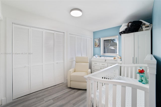 bedroom featuring light wood-type flooring and a nursery area