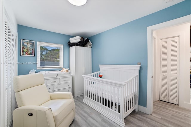 bedroom with light hardwood / wood-style flooring and a nursery area