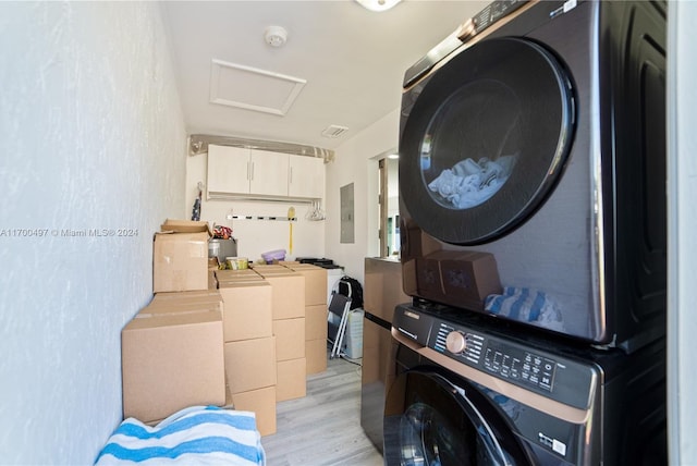 laundry area with electric panel, light hardwood / wood-style flooring, and stacked washer / drying machine