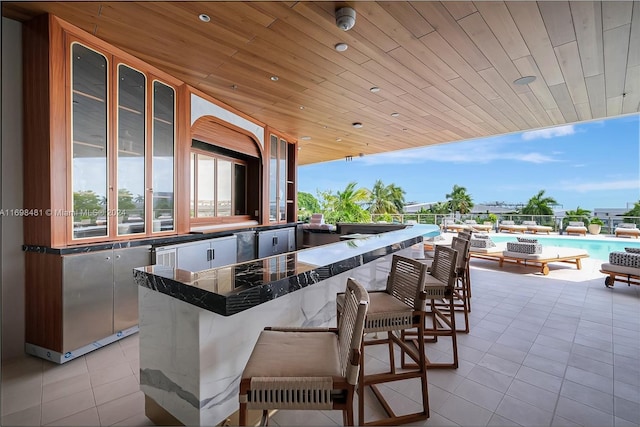 view of patio with an outdoor kitchen, a fenced in pool, and a bar