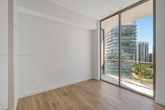 spare room with expansive windows and light hardwood / wood-style floors