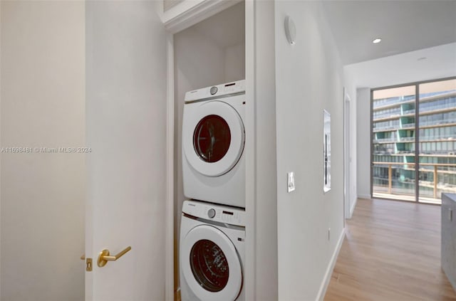 washroom with stacked washing maching and dryer and light hardwood / wood-style floors