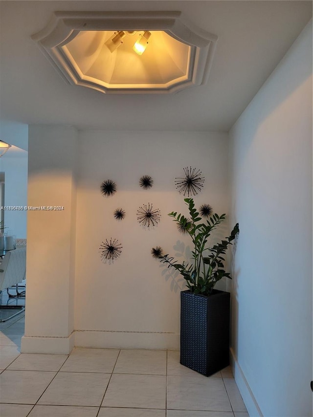 hall featuring a tray ceiling and tile patterned flooring