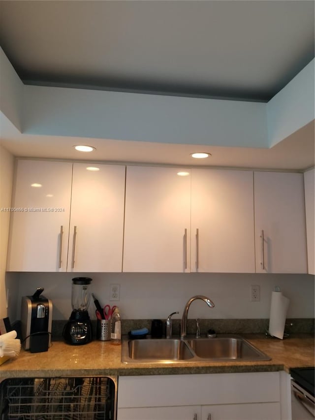 kitchen featuring white cabinetry, sink, and range