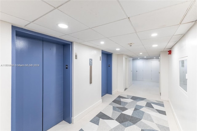 hallway featuring a paneled ceiling and elevator