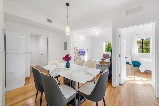 dining room with baseboards, electric panel, light wood-type flooring, and visible vents