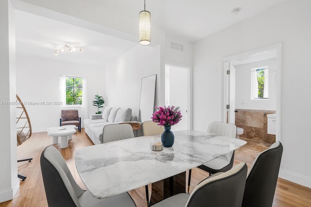 dining room featuring visible vents, light wood finished floors, baseboards, and a healthy amount of sunlight