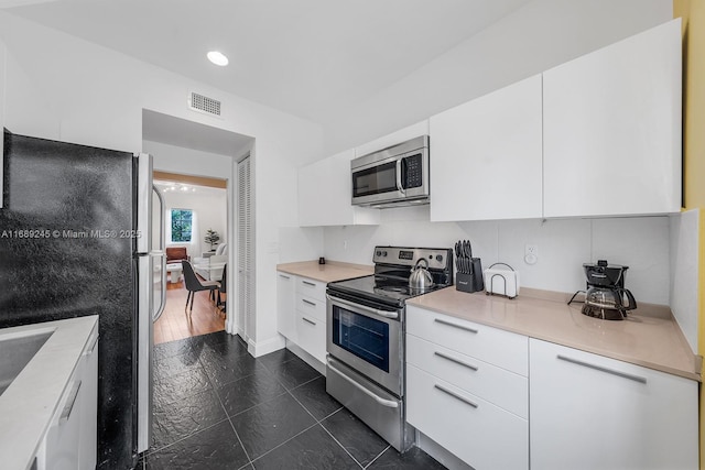 kitchen with visible vents, appliances with stainless steel finishes, modern cabinets, light countertops, and white cabinets