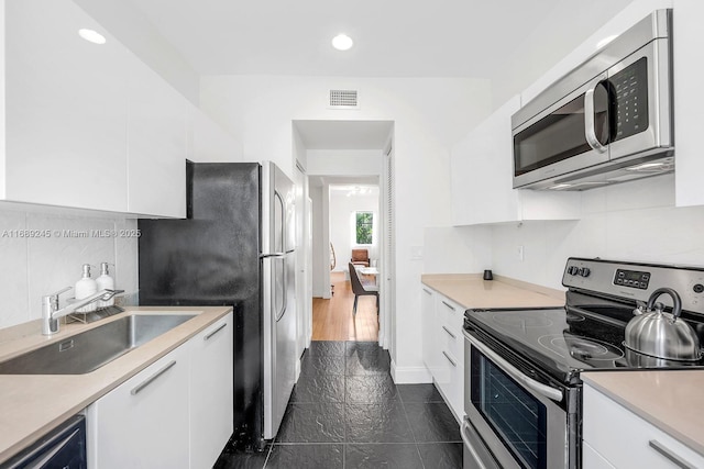 kitchen with visible vents, appliances with stainless steel finishes, a sink, light countertops, and white cabinetry