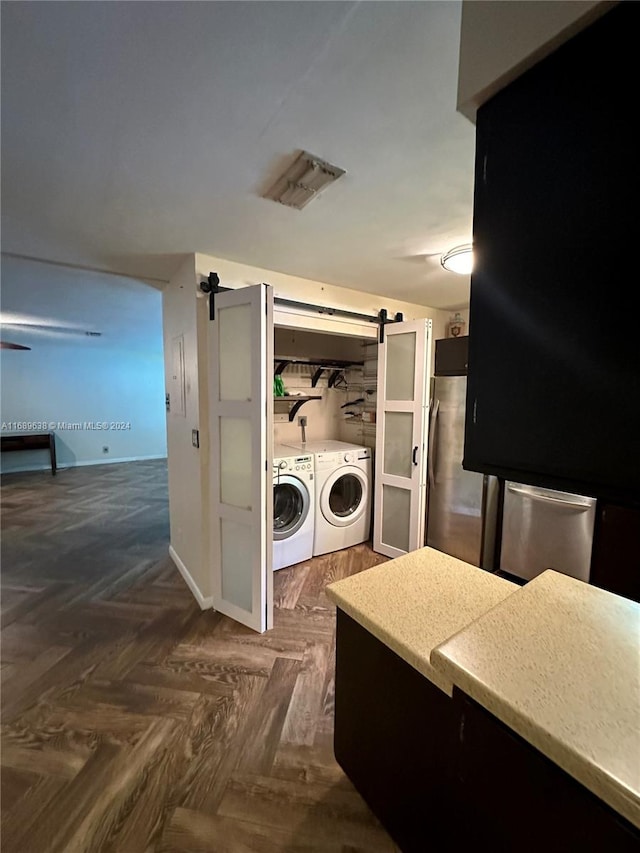 washroom with washer and dryer, a barn door, and dark parquet floors