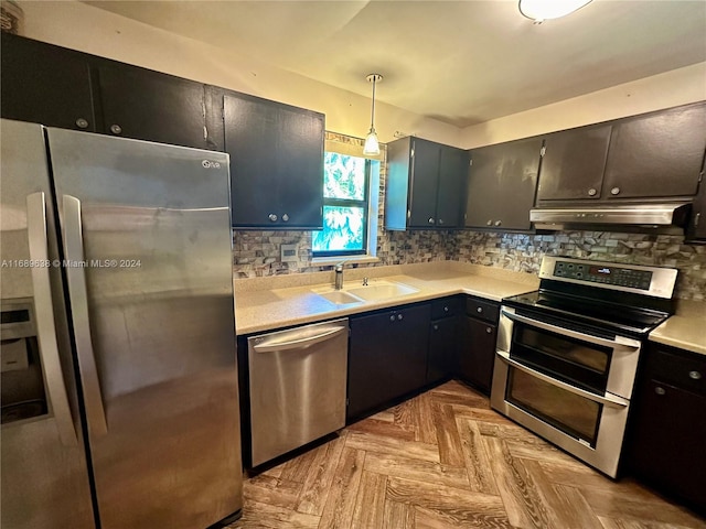 kitchen featuring pendant lighting, light parquet floors, sink, decorative backsplash, and stainless steel appliances